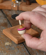 Mader Tarantella On Stage mini spinning top in an adult hand in the Babipur playroom. 