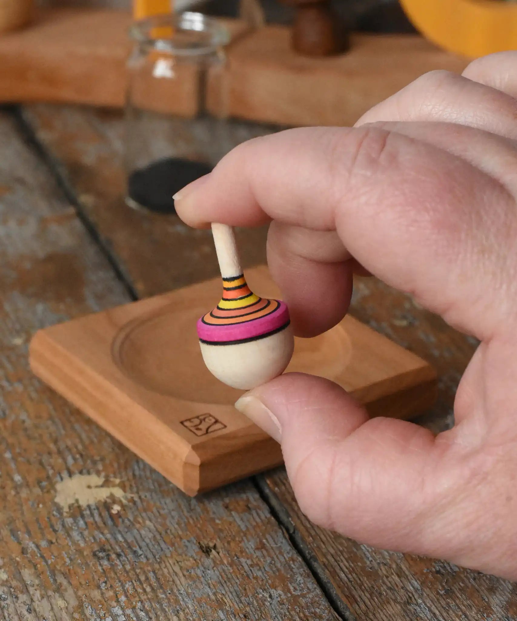 Mader Tarantella On Stage mini spinning top in an adult hand in the Babipur playroom. 