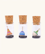 Three Mader tarantella spinning tops in their glass cork topped storage jars.