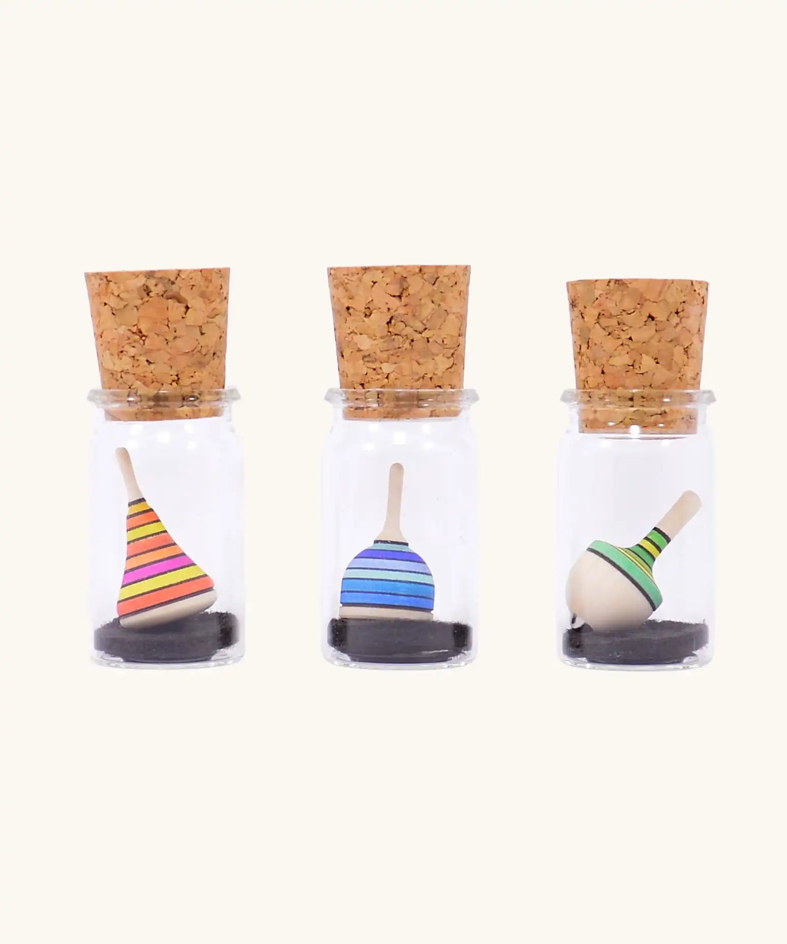 Three Mader tarantella spinning tops in their glass cork topped storage jars.