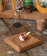 Mader Tarantella On Stage mini spinning top and plate set placed on a desk in the Babipur playroom. 