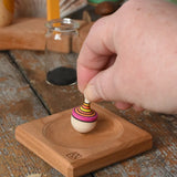 Mader Tarantella On Stage mini spinning top in an adult hand in the Babipur playroom. 