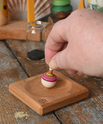 Mader Tarantella On Stage mini spinning top in an adult hand in the Babipur playroom. 