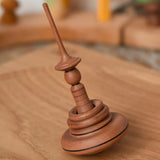 Mader Helene's Captive Rings Apple Spinning Top placed on an oeak spinning plate in the Babipur playroom. 