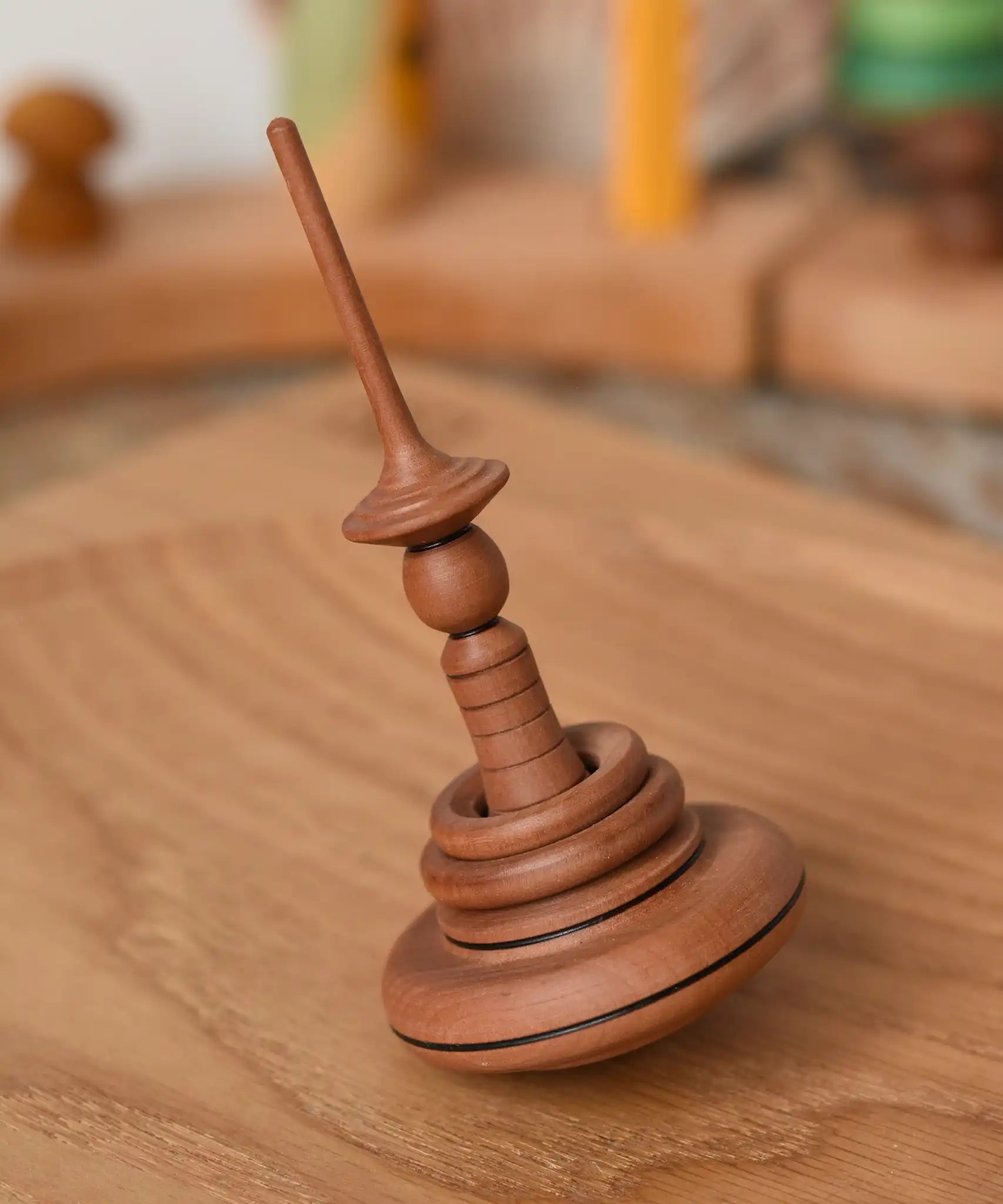 Mader Helene's Captive Rings Apple Spinning Top placed on an oeak spinning plate in the Babipur playroom. 