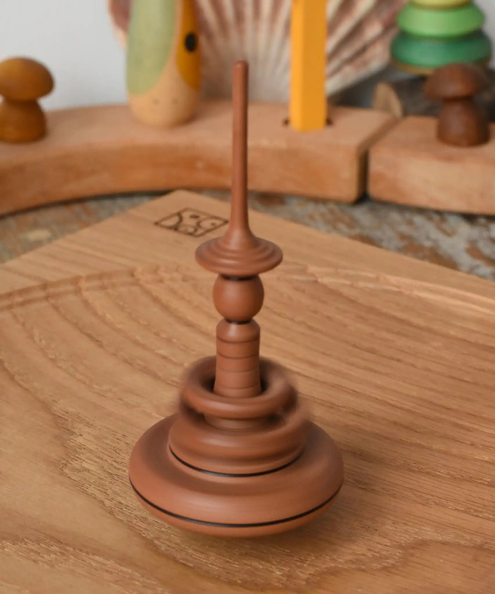 Mader Helene's Captive Rings Apple Spinning Top spinning in motion on an oak spinning plate in the Babipur playroom.
