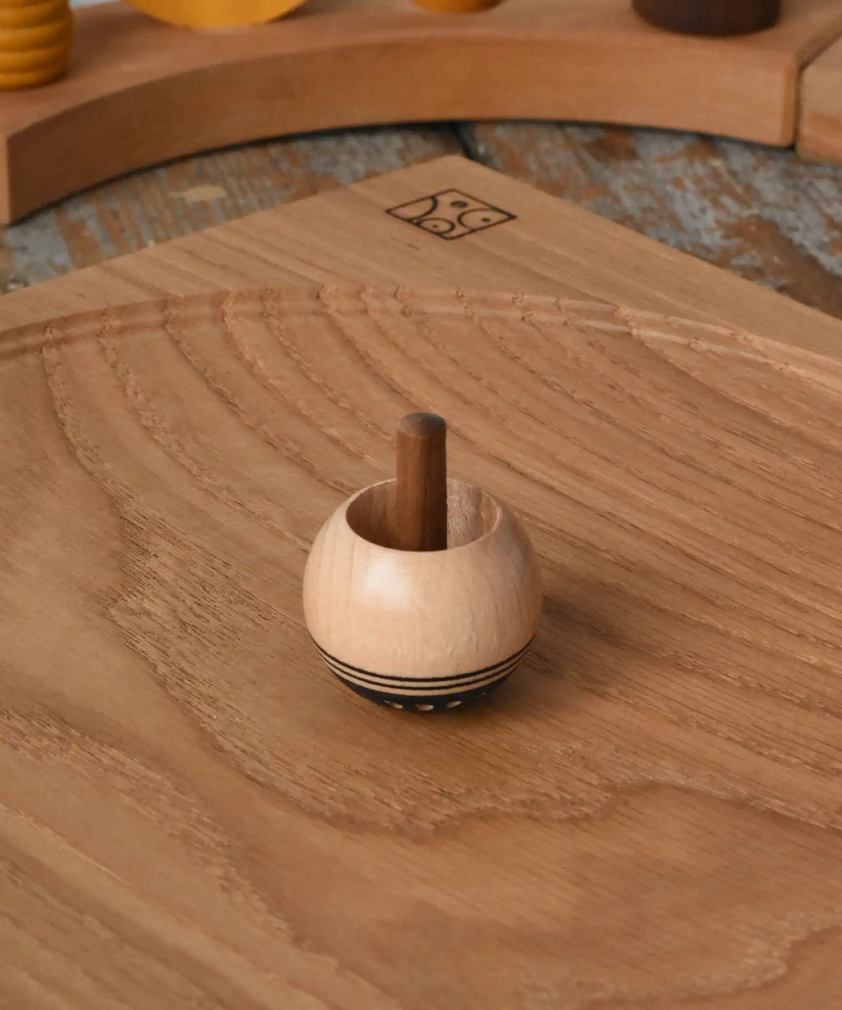 Mader orient turn-over spinning top placed on an oak spinning plate on a  wooden desk in the Babipur playroom.