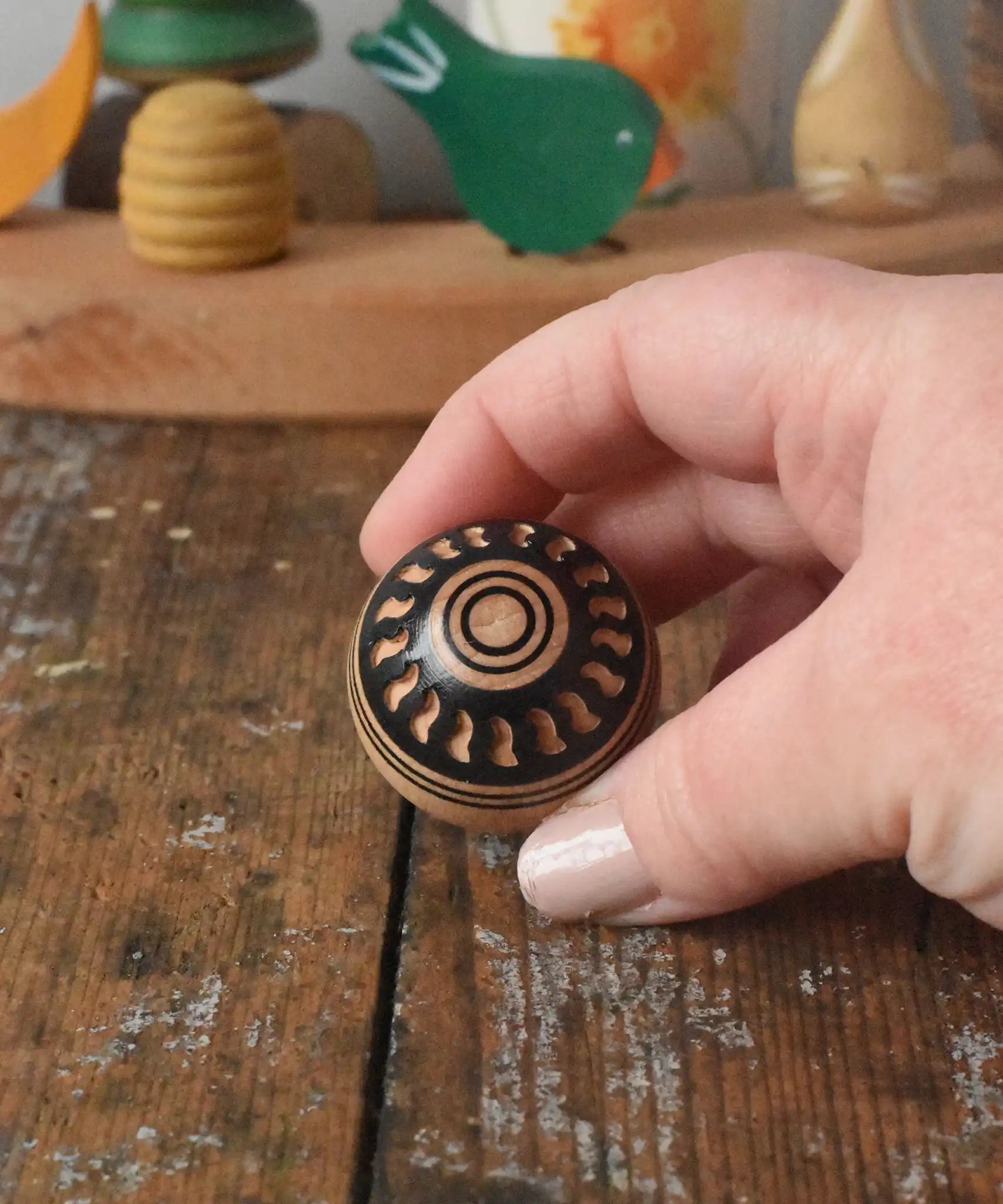Mader orient turn-over spinning top shown in an adult's hand.