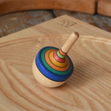 Mader traditional rainbow striped spinning top placed on an ash wood spinning plate in the Babipur playroom. 