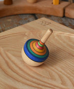 Mader traditional rainbow striped spinning top placed on an ash wood spinning plate in the Babipur playroom. 