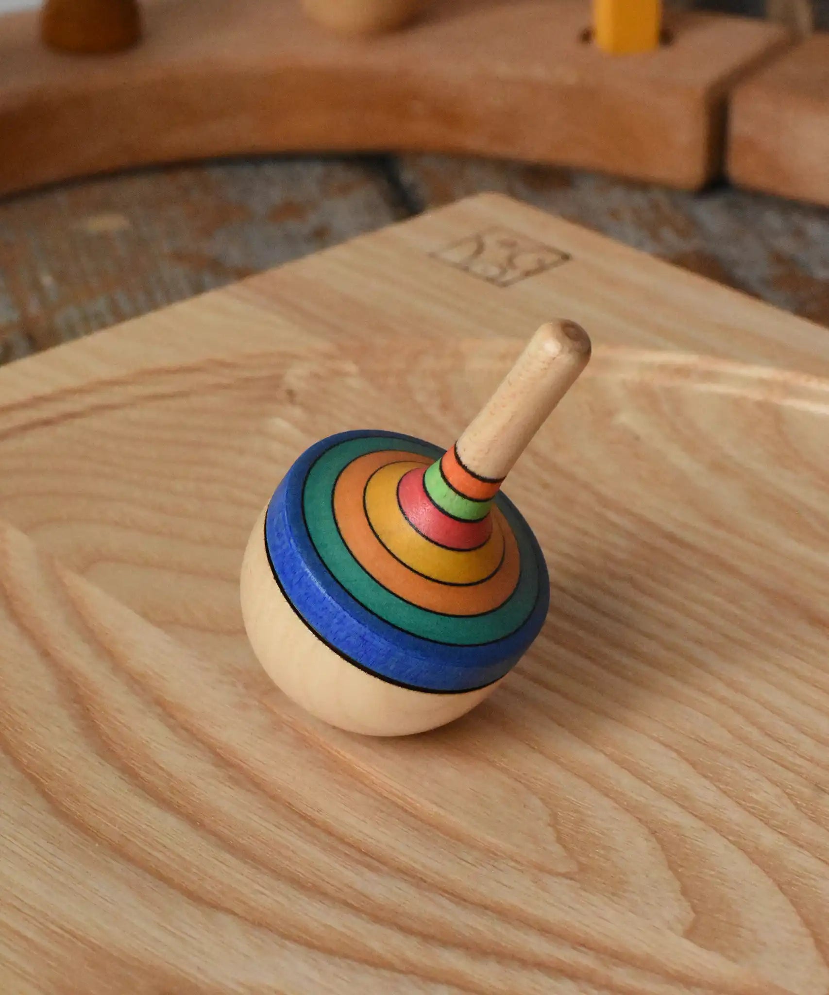 Mader traditional rainbow striped spinning top placed on an ash wood spinning plate in the Babipur playroom. 