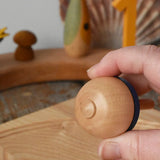 Bottom of the Mader traditional rainbow striped spinning top in an adult's hand.