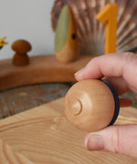 Bottom of the Mader traditional rainbow striped spinning top in an adult's hand.
