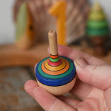 Mader traditional rainbow striped spinning top in an adult hand.