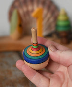 Mader traditional rainbow striped spinning top in an adult hand.