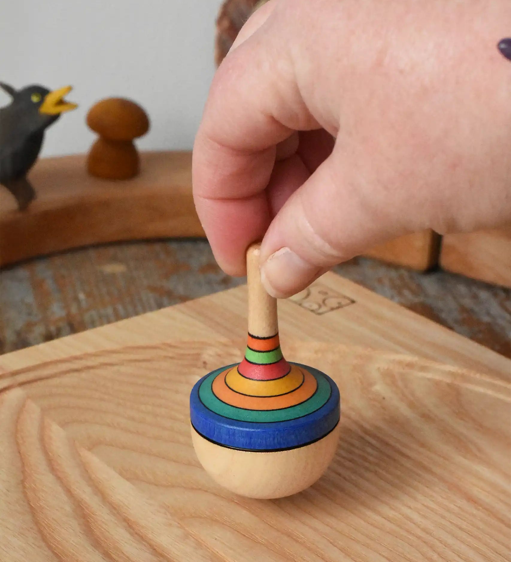 Mader traditional rainbow striped spinning top being placed on an ask spinning plate in the Babipur playroom. 