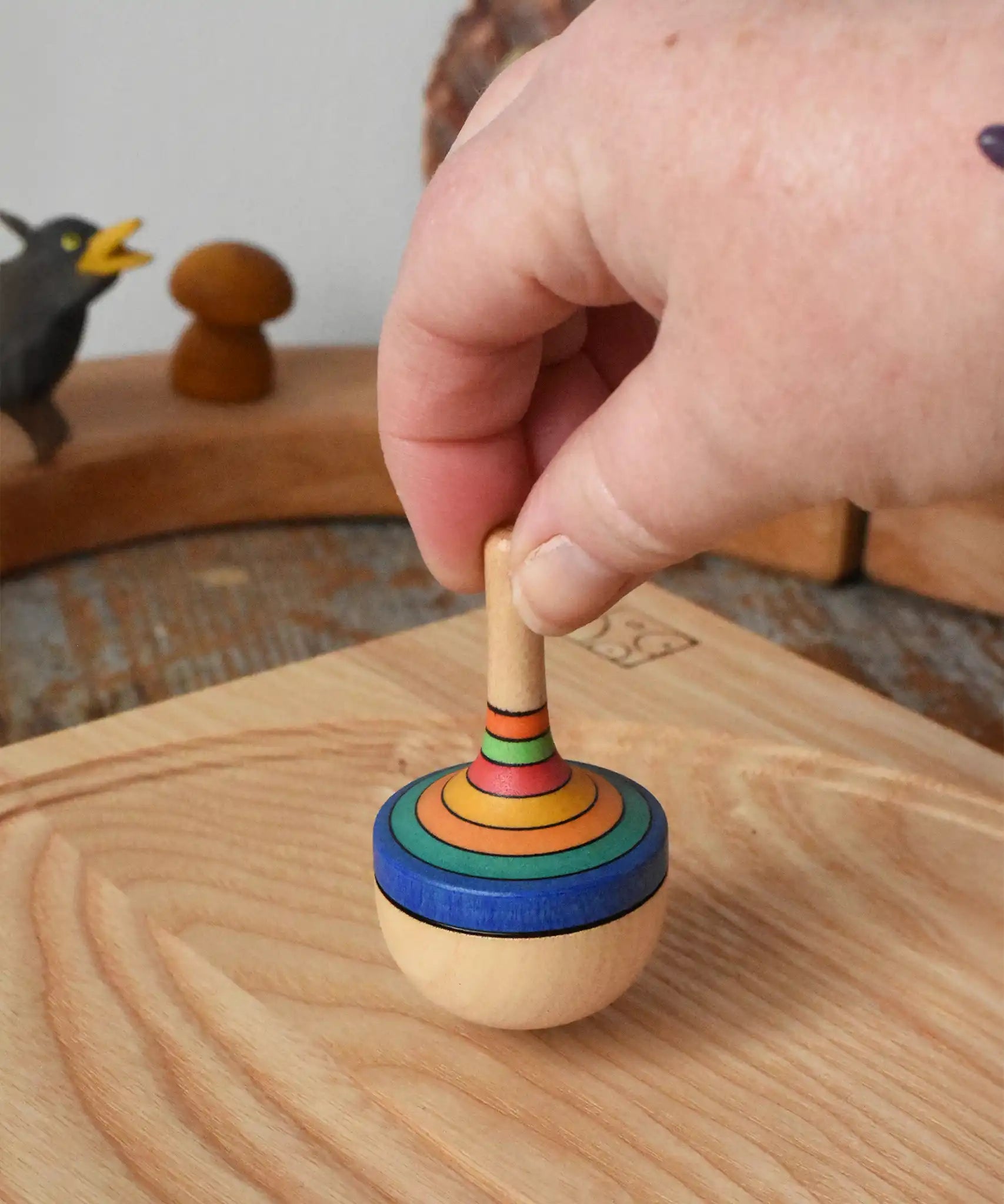 Mader traditional rainbow striped spinning top being placed on an ask spinning plate in the Babipur playroom. 