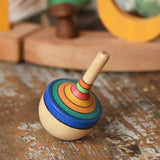 Mader traditional rainbow striped spinning top placed on a wooden surface in the Babipur playroom. 