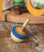 Mader traditional rainbow striped spinning top placed on a wooden surface in the Babipur playroom. 
