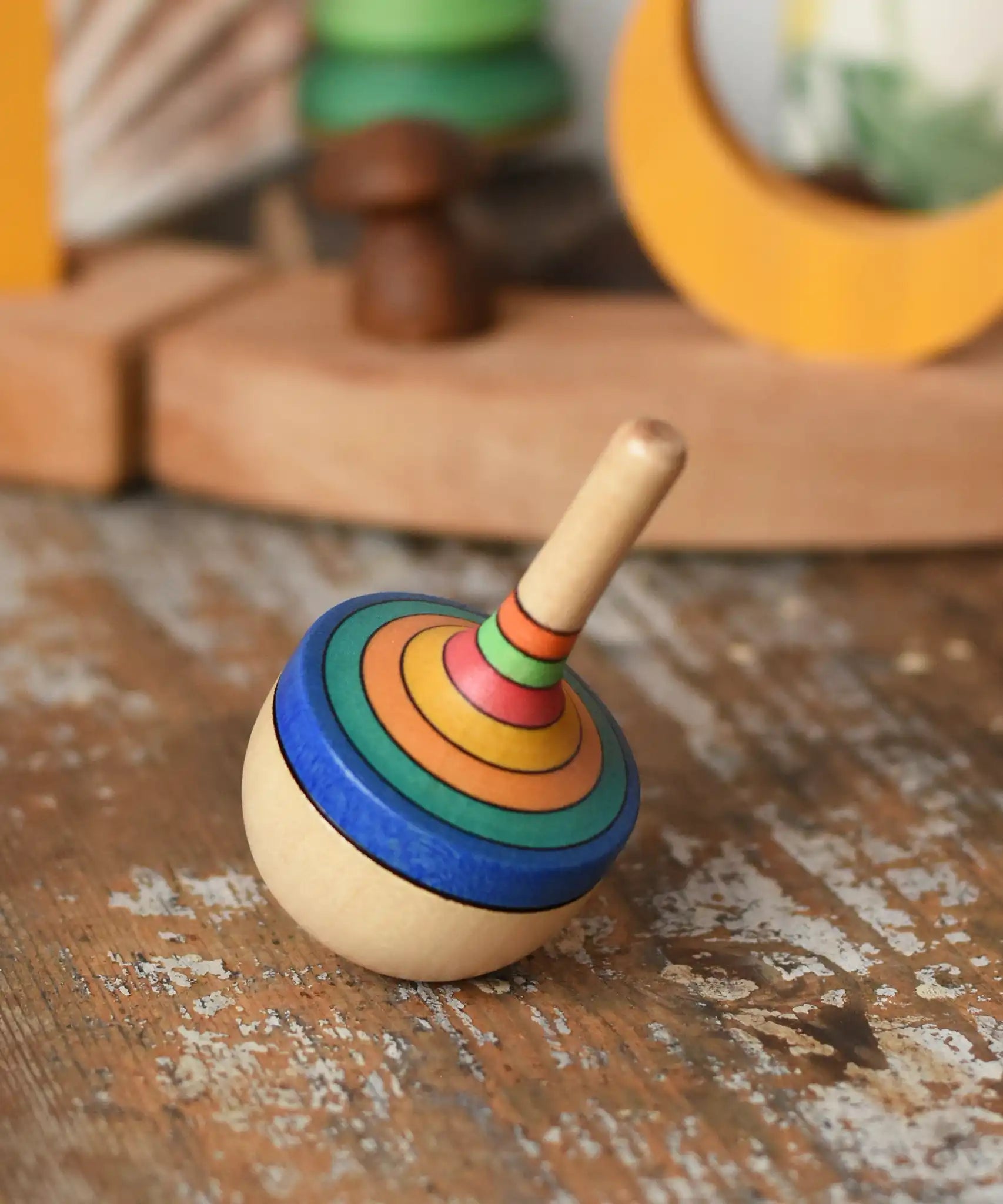 Mader traditional rainbow striped spinning top placed on a wooden surface in the Babipur playroom. 