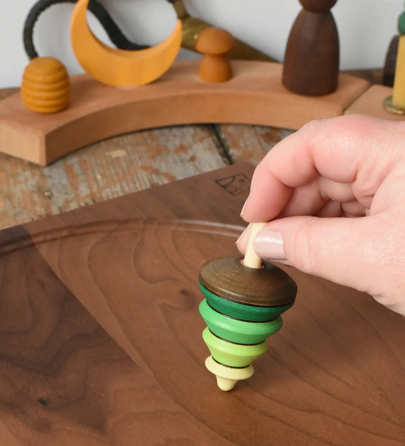 Mader Kreiselmanufaktur tree spinning top being placed on a walnut spinning plate in the Babipur playroom.