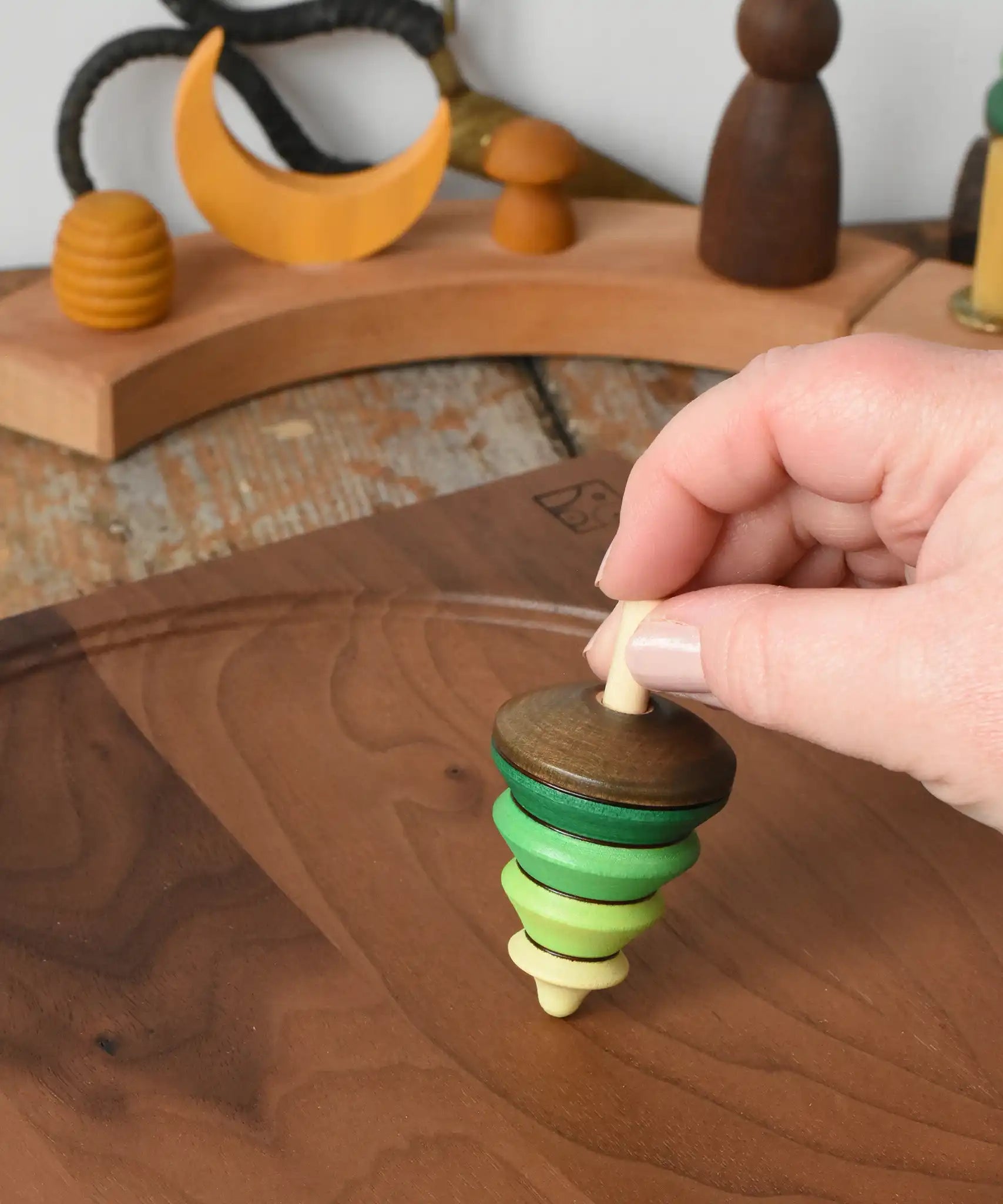 Mader Kreiselmanufaktur tree spinning top being placed on a walnut spinning plate in the Babipur playroom.