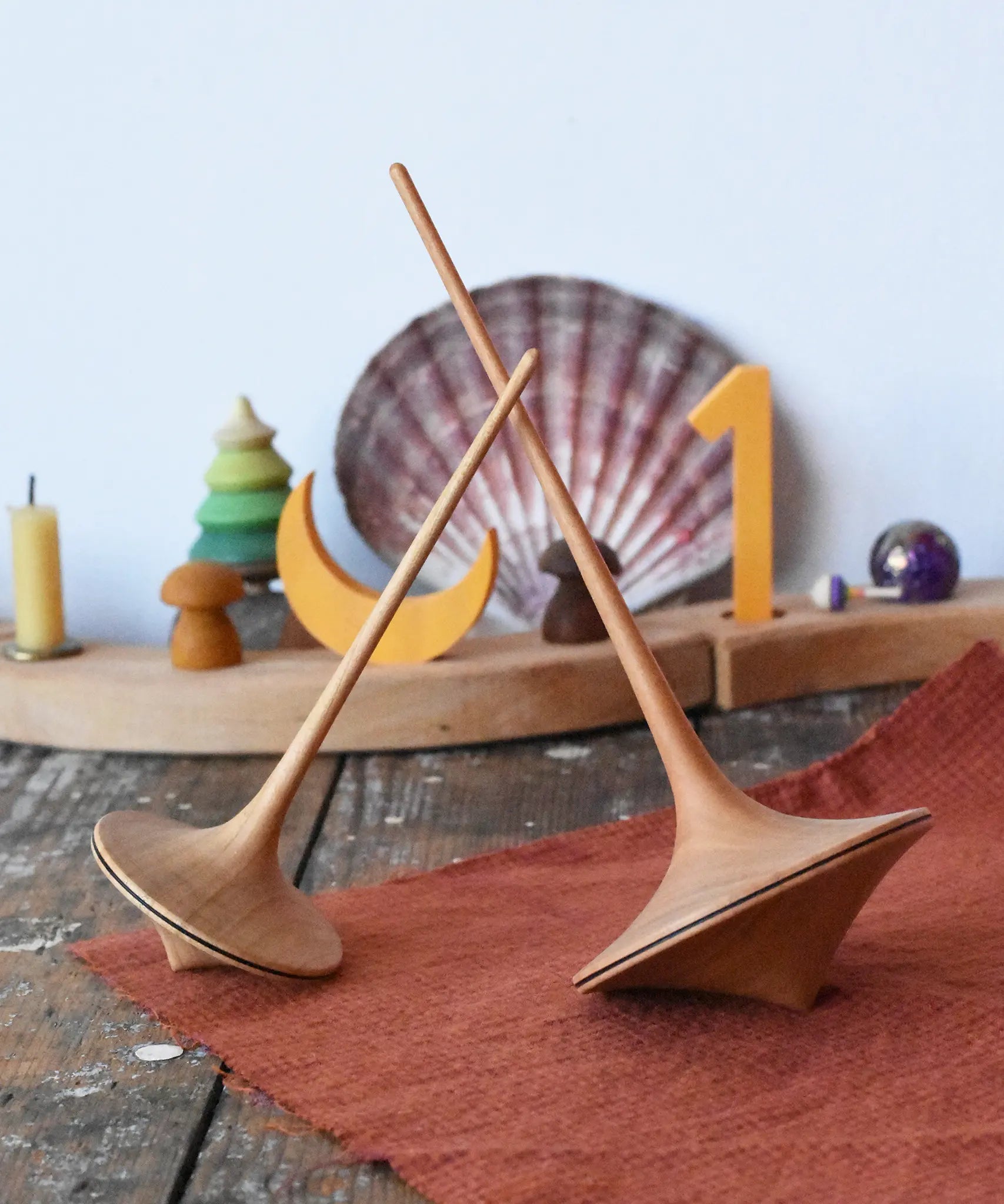 Mader trumpo spinning tops 75mm and 55mm placed on a wooden surface in the Babipur playroom.