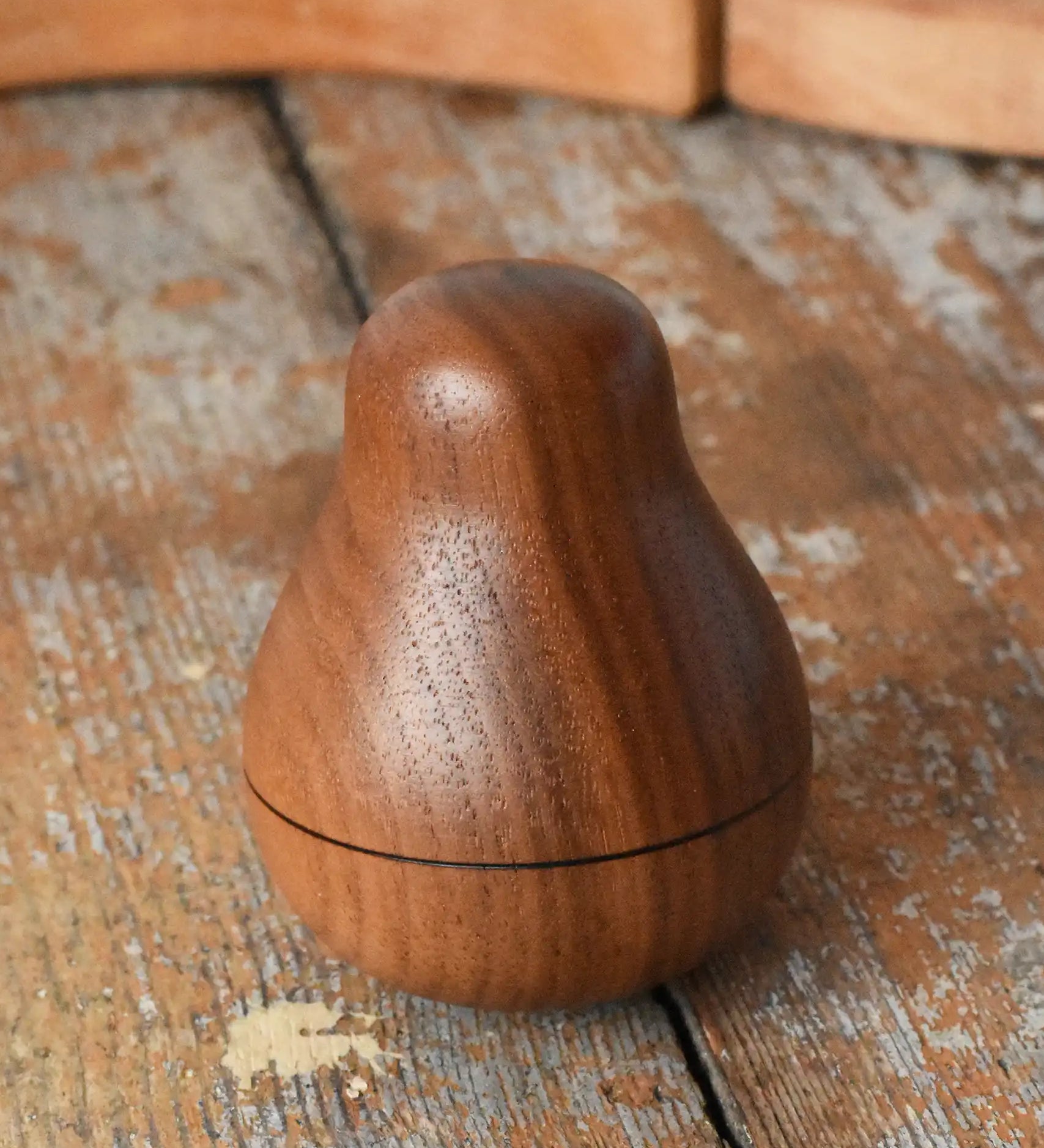 Mader Kreiselmanufaktur walnut roly-poly pear wooden toy placed on a wooden surface in the Babipur playroom. 