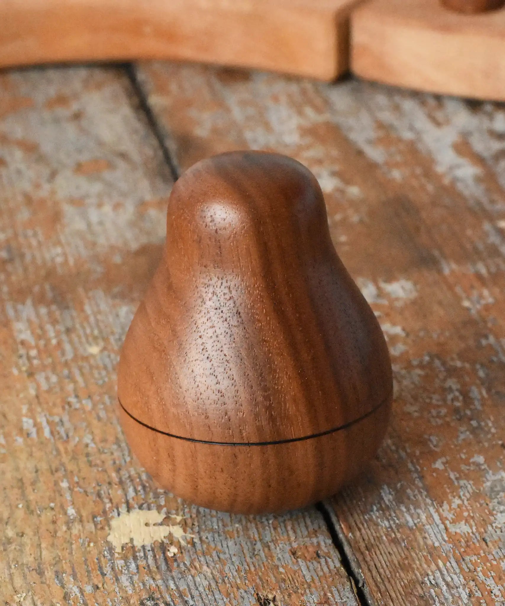 Mader Kreiselmanufaktur walnut roly-poly pear wooden toy placed on a wooden surface in the Babipur playroom. 