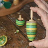 Thunderbolt spinner from the Mader Kreiselmanufaktur green grass spinning top learning set in an adult's hand in the Babipur playroom.