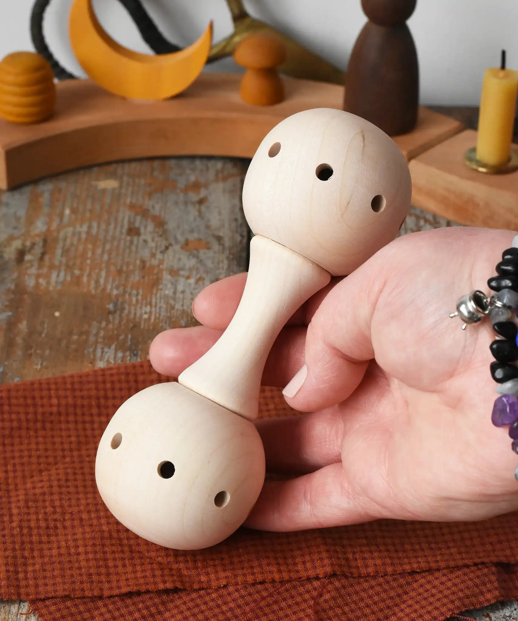 Mader Kreiselmanufaktur traditional wooden baby rattle in an adult's hand in the Babipur playroom. 