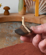 Mader Charlie finger spinning top shown resting on an adult's hand.