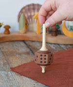 Mader Dice Spinning Top held upright by an adult's hand in the Babipur playroom.