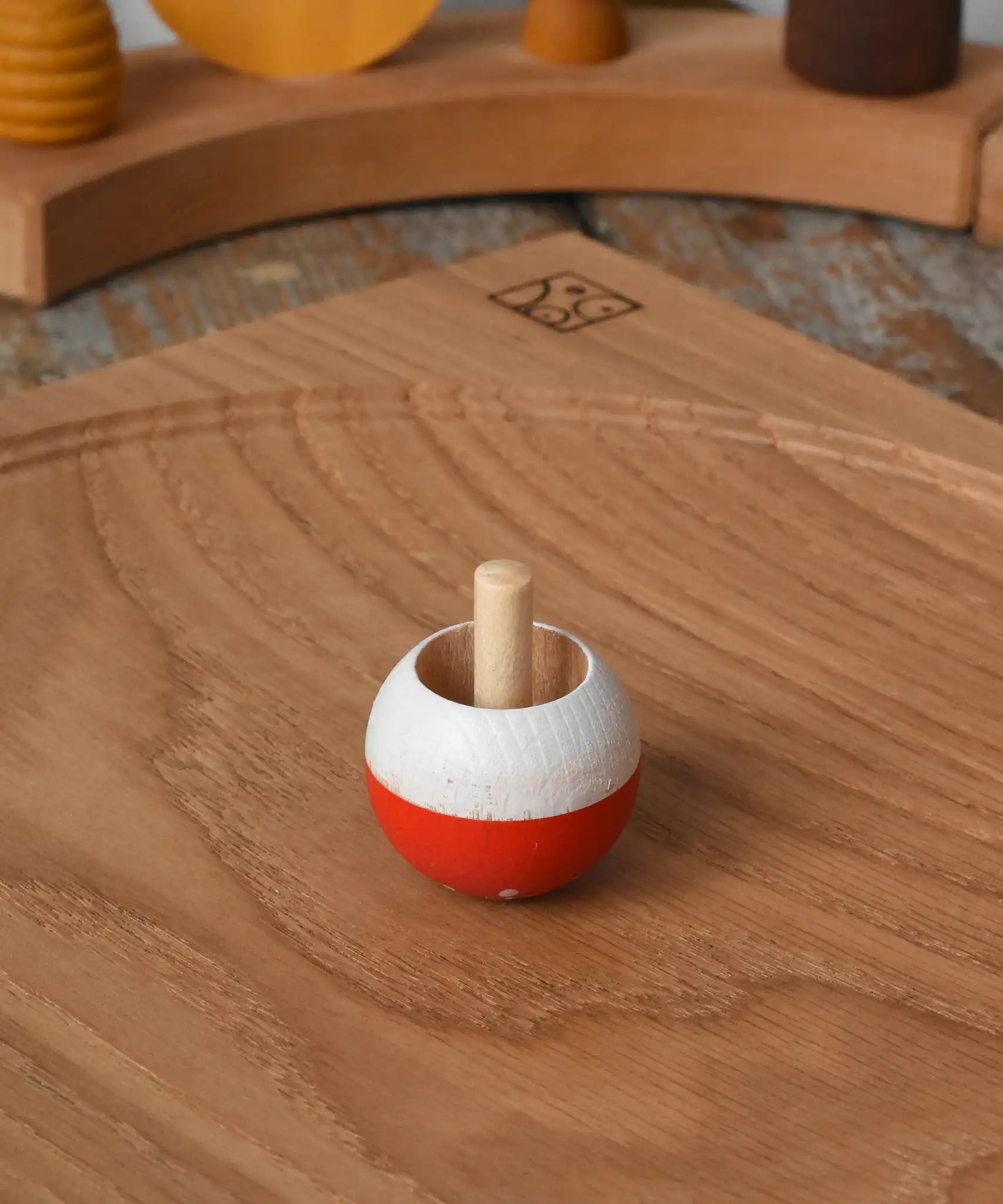 Mader Kreiselmanufaktur fly agaric mushroom turn over spinning top placed on an oak spinning plate in the Babipur playroom.