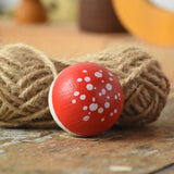 Close up of the top of the Mader Kreiselmanufaktur fly agaric mushroom turn over spinning top placed on a wooden surface n the Babipur playroom.
