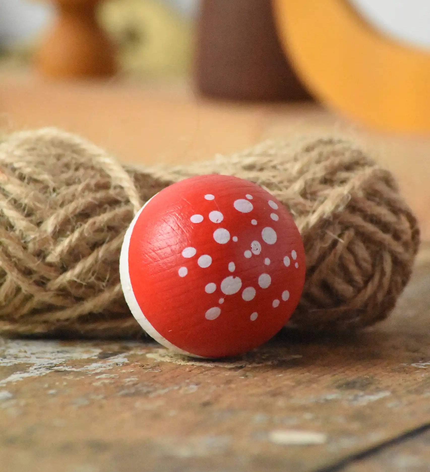 Close up of the top of the Mader Kreiselmanufaktur fly agaric mushroom turn over spinning top placed on a wooden surface n the Babipur playroom.