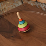 Mader harlekin spinning top placed on a walnut wood plate on a wooden surface in the Babipur playroom.