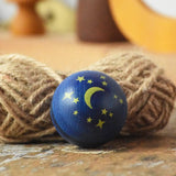 Close up of the moon and stars design on the top of the Mader Luna turn over spinning top wooden toy. 
