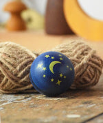 Close up of the moon and stars design on the top of the Mader Luna turn over spinning top wooden toy. 