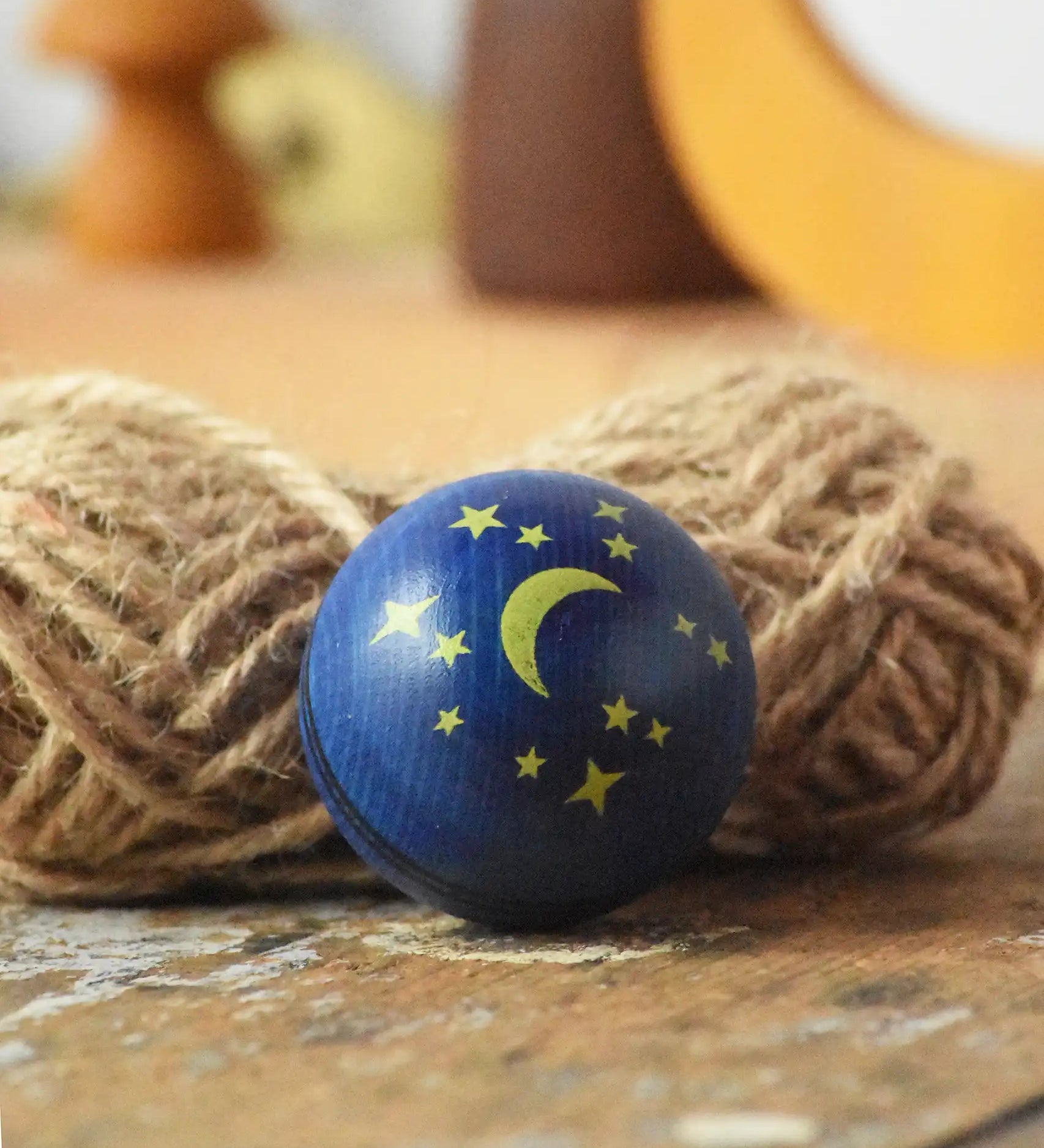 Close up of the moon and stars design on the top of the Mader Luna turn over spinning top wooden toy. 