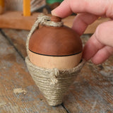 Mader natural profi throw spinning top placed on a wooden surface in the Babipur playroom. An adult hand propping it upright.
