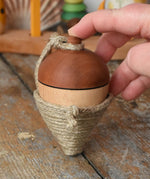 Mader natural profi throw spinning top placed on a wooden surface in the Babipur playroom. An adult hand propping it upright.