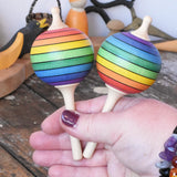 Two Mader Kreiselmanufaktur rainbow lolly spinning tops in an adult's hand.