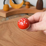 Close up of the top of the Mader Kreiselmanufaktur fly agaric mushroom turn over spinning top in an adult's hand.