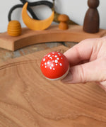 Close up of the top of the Mader Kreiselmanufaktur fly agaric mushroom turn over spinning top in an adult's hand.