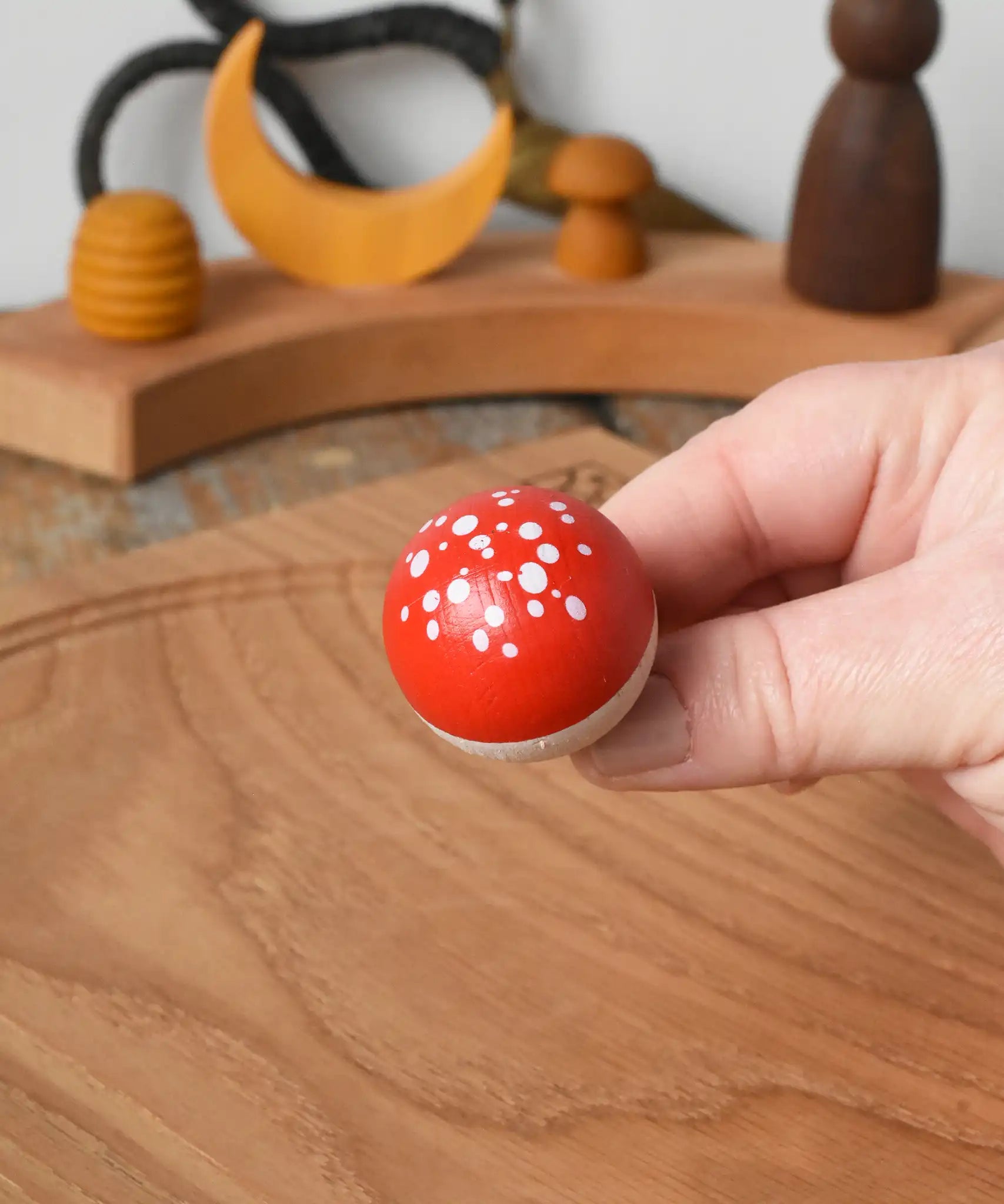 Close up of the top of the Mader Kreiselmanufaktur fly agaric mushroom turn over spinning top in an adult's hand.