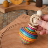 Mader Kreiselmanufaktur ring pull string spinning top placed on a cherry wood spinning plate in the Babipur playroom.