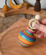 Mader Kreiselmanufaktur ring pull string spinning top placed on a cherry wood spinning plate in the Babipur playroom.