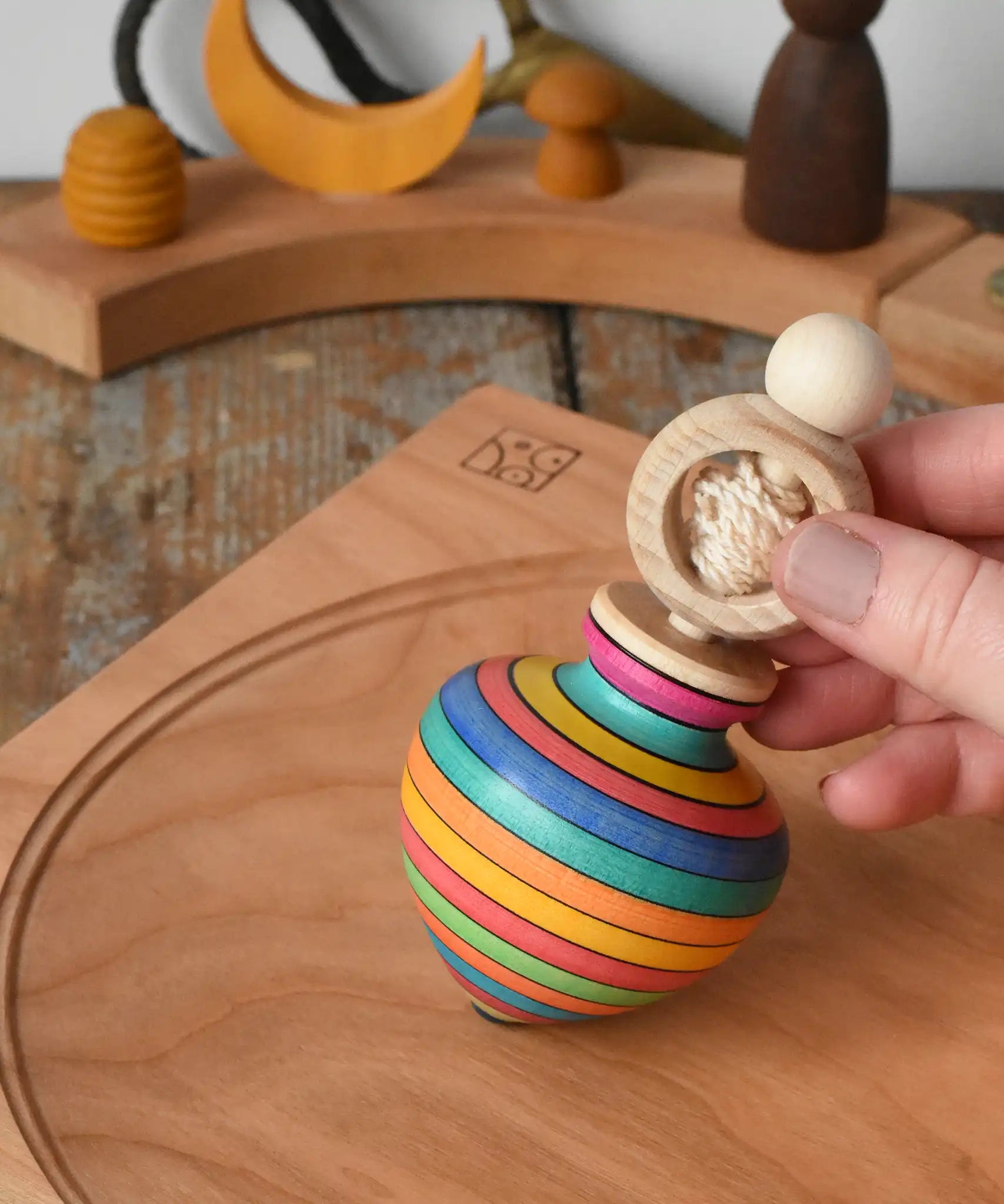 Mader Kreiselmanufaktur ring pull string spinning top placed on a cherry wood spinning plate in the Babipur playroom.