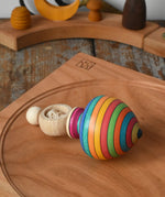 Mader Kreiselmanufaktur ring pull string spinning top placed on a cherry wood spinning plate in the Babipur playroom.